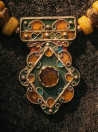 Macro detail of handcrafted green and orange filigree enamel pendant on Tibetan necklace