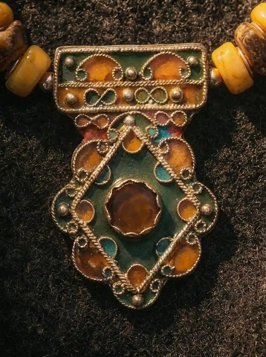 Macro detail of handcrafted green and orange filigree enamel pendant on Tibetan necklace