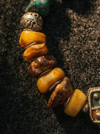 Close-up of natural raw amber beeswax beads and carved metal spacer on Tibetan necklace
