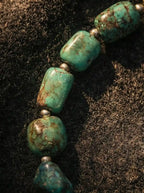 Detail close-up of natural green turquoise tumbled beads with dark brown matrix