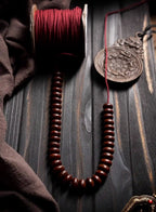 Single strand of bowl-shaped Bodhi seeds being strung with red cord and spool